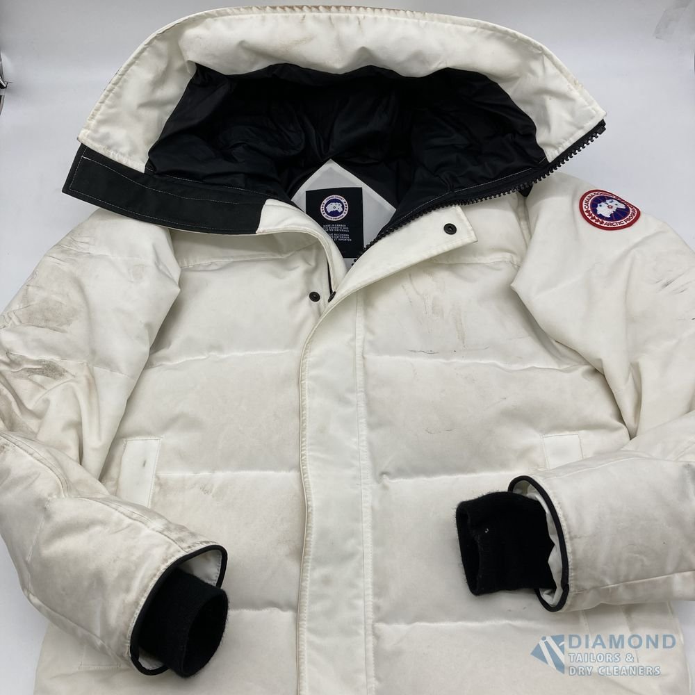 White Canada Goose down parka before cleaning — the sleeves and body are heavily soiled with dark grey-brown marks