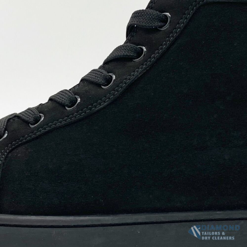 The same Louboutin sneaker after cleaning — the suede restored to a deep, even black