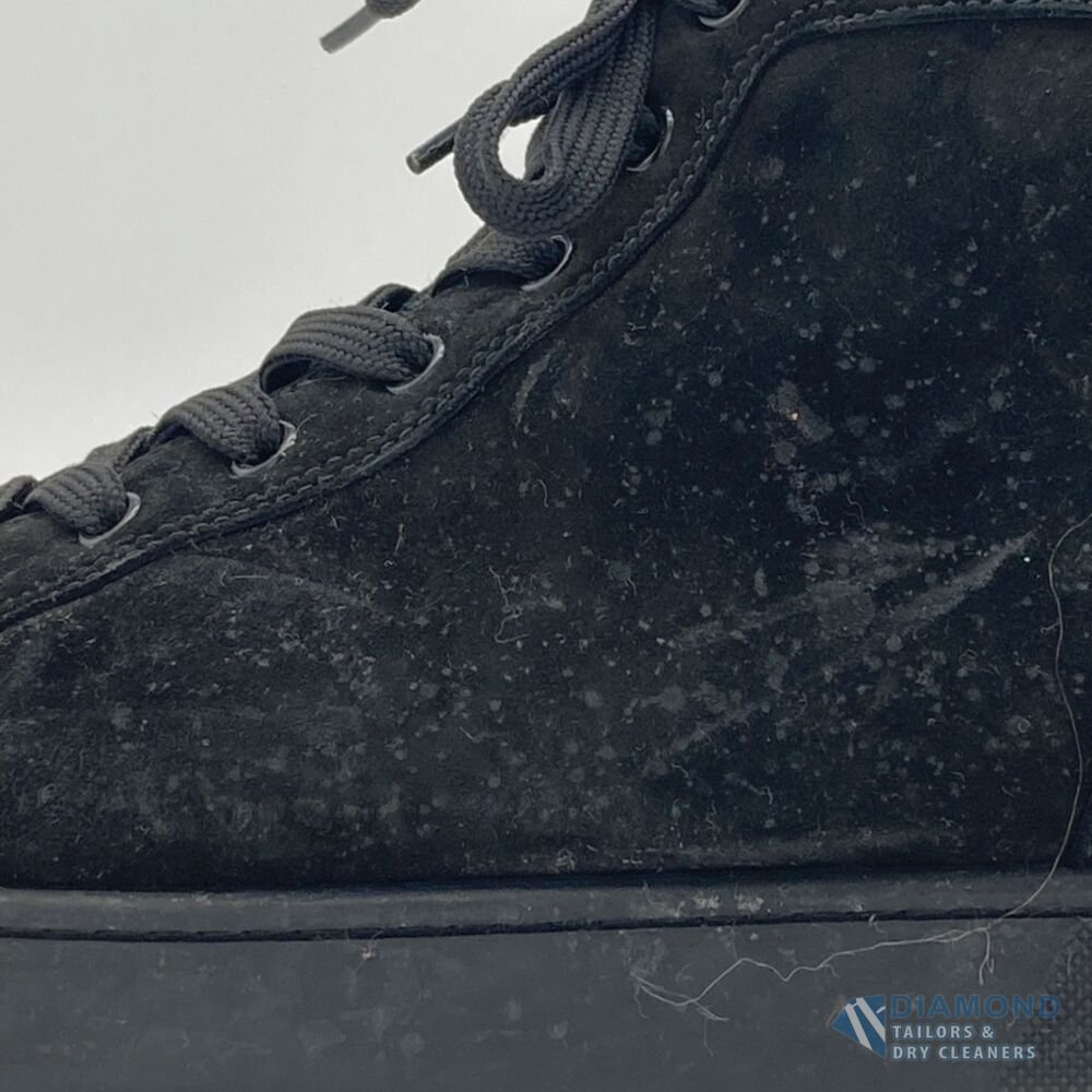 Black suede Christian Louboutin high-top sneaker before cleaning — the suede is dull, greyed and covered in lint