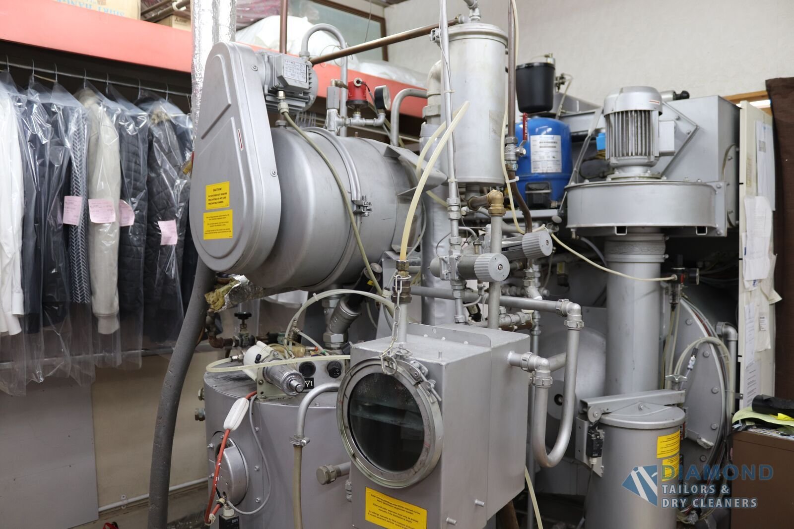 Dry-cleaning machine on the premises at Diamond TDC, with cleaned garments hanging in protective covers alongside